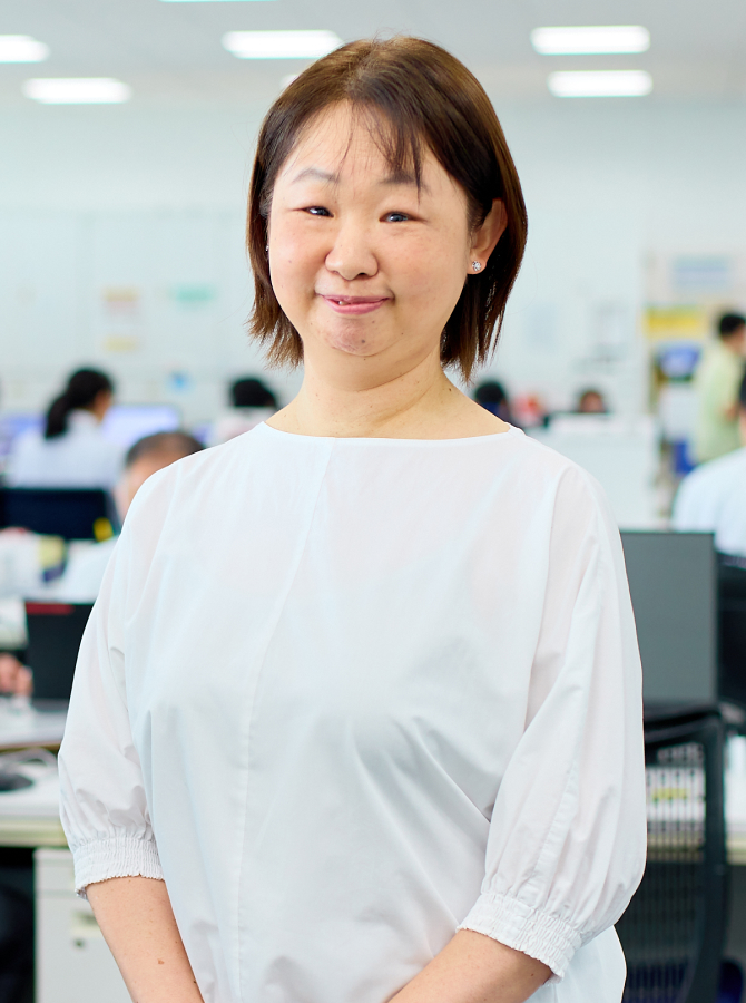 オフィスを背景にした私服のM.A.さんの正面ポートレート